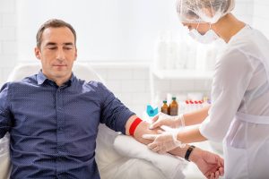 Healthcare professionals drawing blood from a male patient's arm during a clinical visit, representing prostate cancer screening and diagnostic testing.